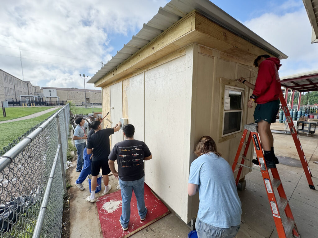 students working on finishing an outdoor shed